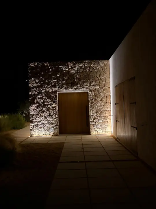 Fachada de piedra y puerta de madera con iluminación nocturna en una villa