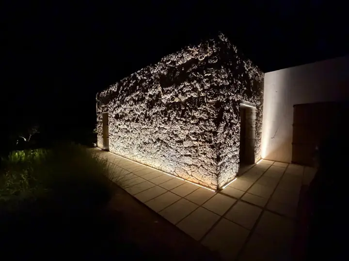 Caseta de piedra con perfil LED enterrado en el pavimento, vista nocturna