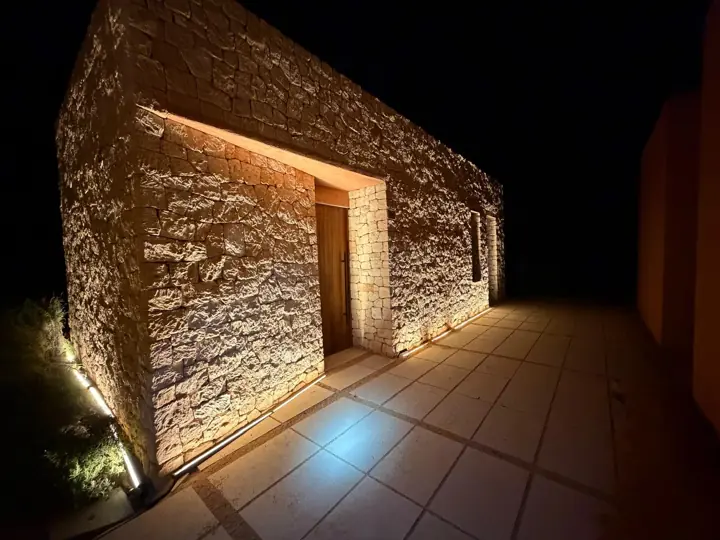 Entrada de una caseta de piedra con luz LED integrada y balizas en el suelo