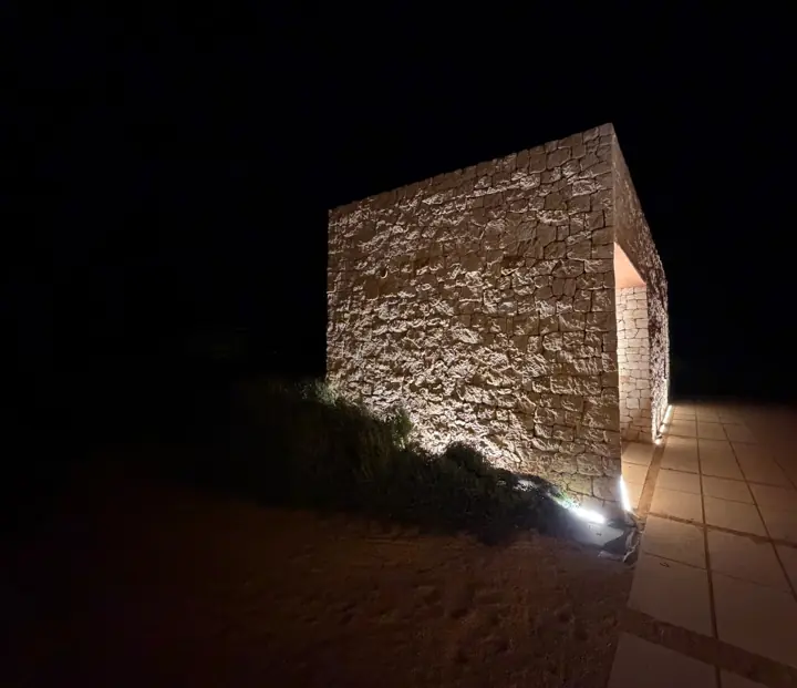 Esquina de una caseta de piedra iluminada de noche con LED