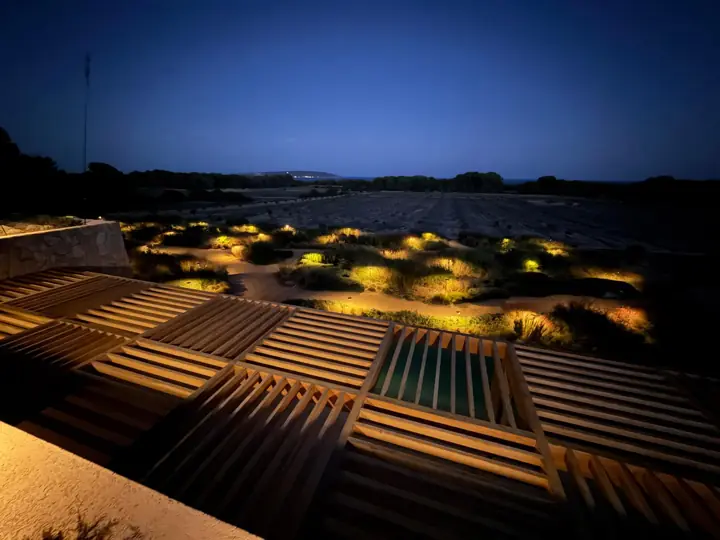 Pérgola de madera y jardín mediterráneo con balizas de iluminación al anochecer